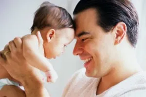 Smiling father holding his young infant forehead to forehead