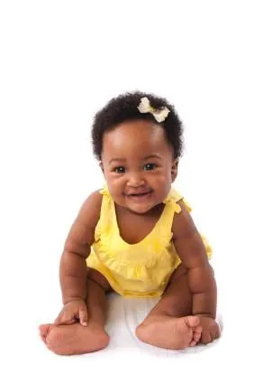 Smiling baby in a yellow outfit sitting up