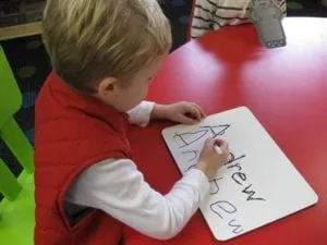 Boy writing his name on a whiteboard