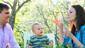 Parents blowing bubbles for their baby outdoors