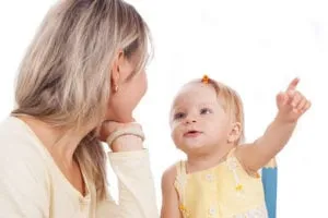 Toddler pointing at something while looking at her mother