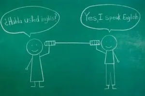 Chalk drawing of two figures on a tin-can phone: “¿Habla usted inglés?” and “Yes, I speak English”
