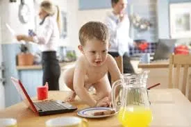 Toddler crawling on a kitchen table, reaching for food and drink by himself