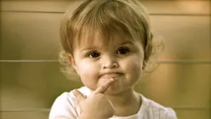 Toddler with a finger on her lips, looking puzzled
