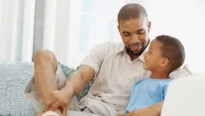 Father and son sitting on a couch talking together