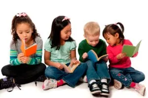 Four young children sitting on the floor reading books