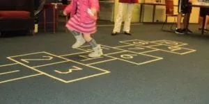 Child jumping on a numbered hopscotch mat
