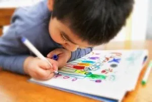 Young boy drawing a colourful picture with markers