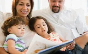 Parents reading a picture book with their two young daughters