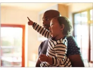 Toddler held by a parent pointing at something, sharing joint attention