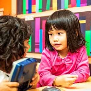 Young girl listening to another child during a conversation at a table