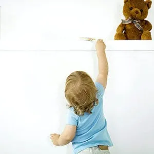 Toddler reaching up toward a teddy bear on a shelf out of reach