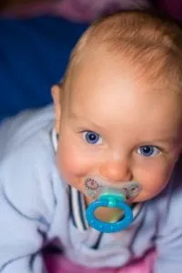 Baby with a pacifier in his mouth looking up