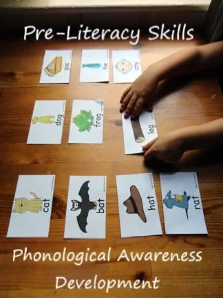 Child’s hands arranging rhyming picture cards such as cat, bat, hat, rat, dog, frog and log on a wooden table