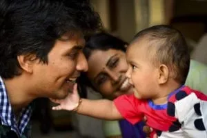 Baby touching a smiling father's face while mother looks on